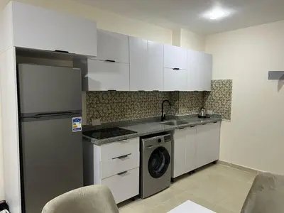 a kitchen with white cabinets and a washing machine at Tiba gollden resort in Hurghada