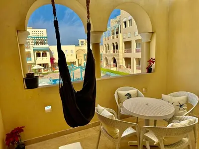 a hammock in a balcony with a table and chairs at Gouna Luxuy Condo Hotel in El Gouna