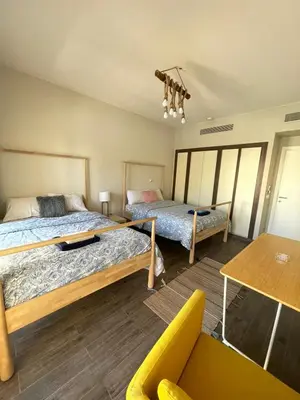 a bedroom with two beds and a yellow couch at Gouna Luxuy Condo Hotel in El Gouna
