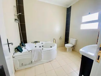 a white bathroom with a tub and a toilet at Happiness Villa Majawish, close to the city center in Hurghada