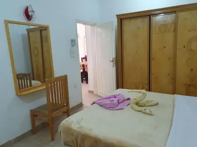 a bedroom with a bed and a chair and a mirror at Sekhmet Appartement 3 chambres in Luxor