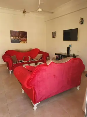 a living room with two red couches and a tv at Sekhmet Appartement 3 chambres in Luxor