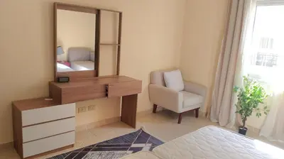a bedroom with a dresser and a mirror and a chair at Palm Beach Piazza Beachfront lovely Apartment in Hurghada