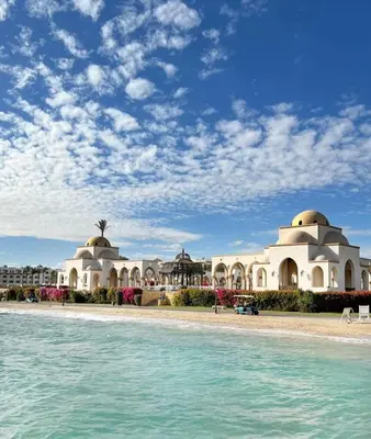 a building on the beach next to the water at Palm Beach Piazza Beachfront lovely Apartment in Hurghada