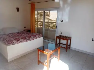 a bedroom with a bed and a table and a window at Amenophis Hotel in Luxor