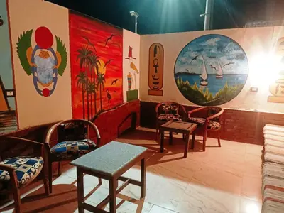 a room with chairs and paintings on the walls at Amenophis Hotel in Luxor