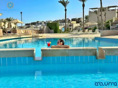 a woman with a drink in a swimming pool at one bedroom chalet,with sea view terrace in Hurghada