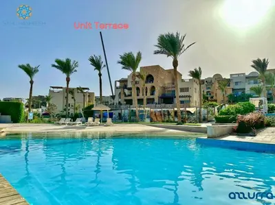 a large swimming pool with palm trees and buildings at one bedroom chalet,with sea view terrace in Hurghada