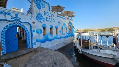 a blue and white boat is docked in the water at Dolty Kato Nubian House By Kato Dool in Aswan