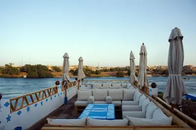 a boat with couches and umbrellas on the water at Dolty Kato Nubian House By Kato Dool in Aswan