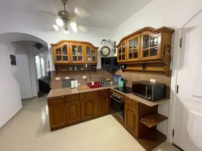 a large kitchen with wooden cabinets and a microwave at 2 Bedroom Ground Floor New Nubia - 2 minutes walk to marina Abu Tig in Hurghada