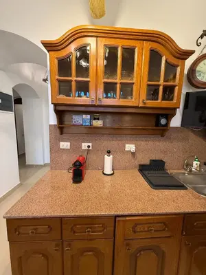a kitchen with wooden cabinets and a counter top at 2 Bedroom Ground Floor New Nubia - 2 minutes walk to marina Abu Tig in Hurghada