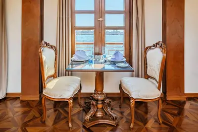 a dining room with a table with two chairs and a window at Princess Farida Luxury Dahabiya Nile Cruise, Every Monday from Luxor to Aswan 4 nights and Every Friday from Aswan to Luxor 3 nights in Luxor