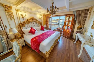 a bedroom with a large bed and a chandelier at Princess Farida Luxury Dahabiya Nile Cruise, Every Monday from Luxor to Aswan 4 nights and Every Friday from Aswan to Luxor 3 nights in Luxor