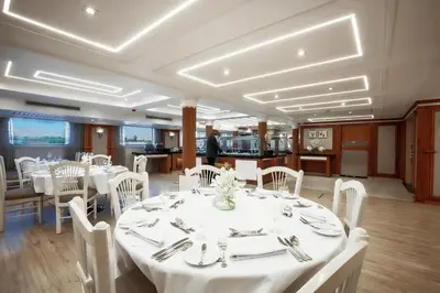 a dining room with white tables and white chairs at Orient Sun Times Nile Cruise-Every Monday from Luxor for 04 & 07 Nights - Every Friday From Aswan for 03 Nights in Luxor