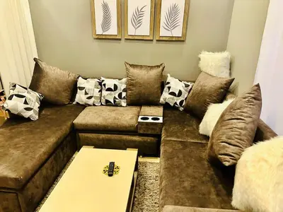 a living room with a brown couch with pillows at Aldau Heights Apartment in Hurghada