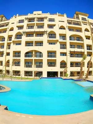 a large building with a large swimming pool in front of it at Aldau Heights Apartment in Hurghada