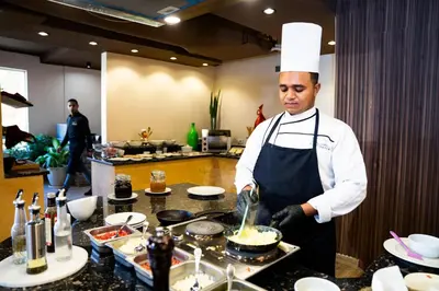 a chef standing in a kitchen preparing food at Al Dora Residence Apartments in Hurghada