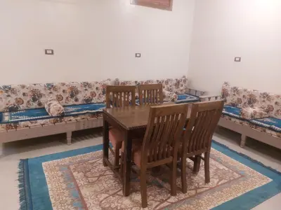 a dining room with a table and chairs and a couch at Rawan apartments in Luxor