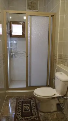 a bathroom with a toilet and a glass shower at Rawan apartments in Luxor