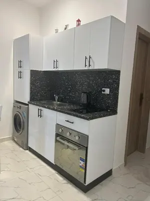 a kitchen with white cabinets and a sink and a dishwasher at La Prestigia in Hurghada