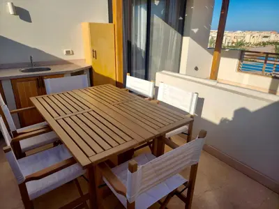 a wooden table and chairs in a room with a window at Sunrise to Sunset Rooftop Panorama - El Gouna Shedwan in Hurghada