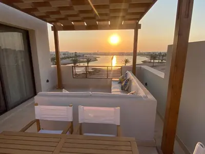 two chairs and a hot tub on a balcony with the sunset at Sunrise to Sunset Rooftop Panorama - El Gouna Shedwan in Hurghada