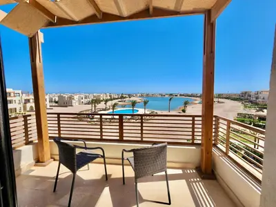 a balcony with chairs and a view of a pool at Sunrise to Sunset Rooftop Panorama - El Gouna Shedwan in Hurghada