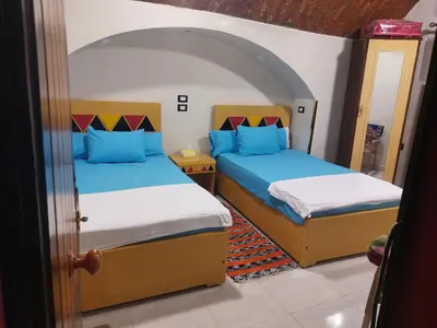 a bedroom with two beds with blue pillows at Lale Hoste in Nag` el-Ramla