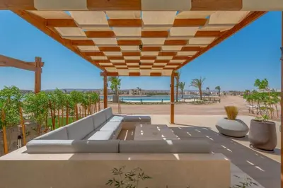 a patio with a couch under a wooden roof at Tranquil 2BR in Shedwan I El Gouna I Pool and Lagoon View in Hurghada