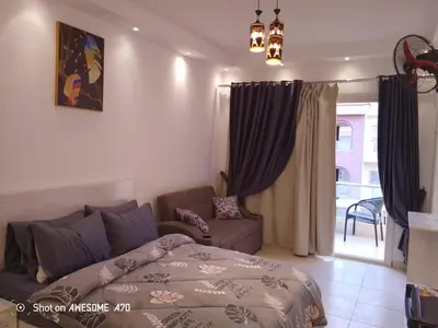 a bedroom with a bed and a couch and a window at الغردقة كومباوند فلورانزا خمسين in Hurghada
