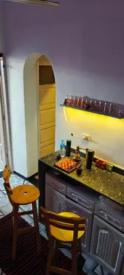 a kitchen with a counter with two chairs and a table at MRHostel Luxor in Luxor