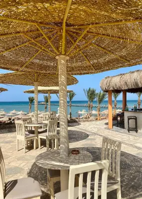 a table and chairs under an umbrella on the beach at Apartment in el karma aqua beach resort hurghada near el gouna 3 in Hurghada