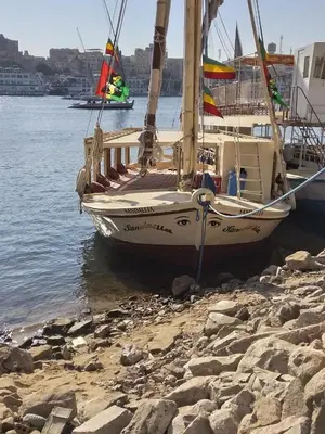 a boat sitting on the shore next to the water at Sailing spirit in Aswan