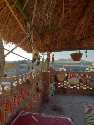 a straw roofed building with chairs and tables at Mourad morsy مراد in Najâ€˜ al MadÄbb