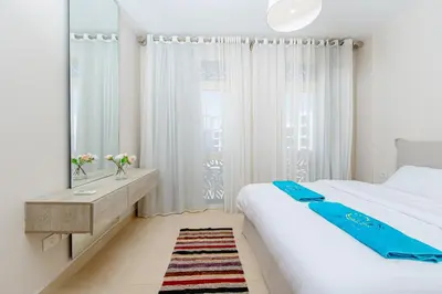 a white bedroom with a large bed and a mirror at Delightful Gateway in Mangroovy in Hurghada