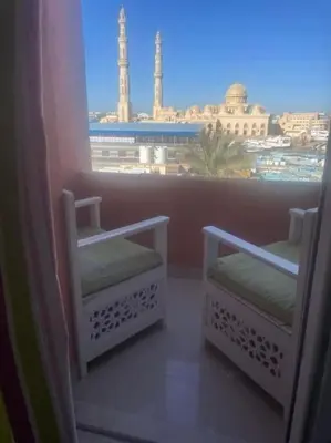 a balcony with two chairs and a view of a city at Sunny Sea View Studio Marina on private roof in Hurghada