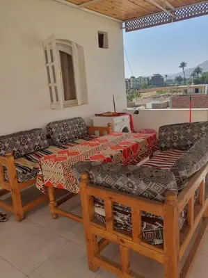 a room with two couches and a table and chairs at Sekhmet Appartement sur le roof in Luxor