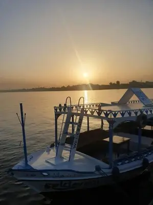 a small boat sitting in the water at sunset at Sekhmet Appartement sur le roof in Luxor