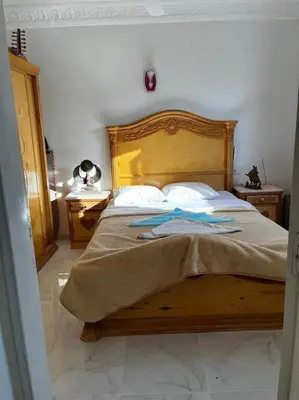 a bedroom with a wooden bed with two pillows at Sekhmet Appartement sur le roof in Luxor
