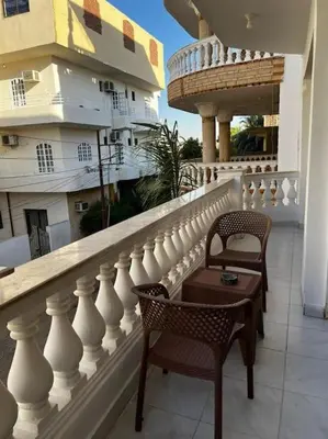 a balcony with two chairs and a table on a building at Sekhmet Appartement 2 chambres in Luxor