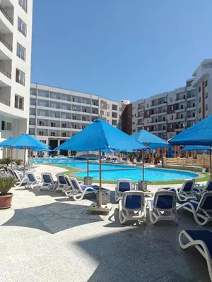 a group of chairs and blue umbrellas next to a pool at Tiba Golden Resort apartment 45 with beach access in Hurghada