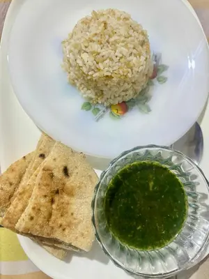 a plate of food with rice and a bowl of green sauce at SEO House in Aswan
