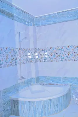 a bath tub in a bathroom with blue tiles at king valley House in ‘Ezbet Abu Ḥabashi