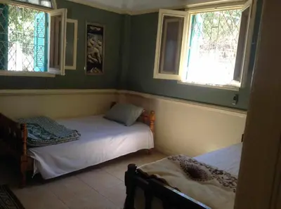a bedroom with two beds and two windows at Luxor Stables Apartment in Luxor