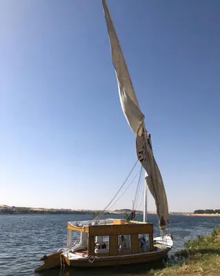 a sail boat is sitting on the water at faloka Farha Camp in Aswan
