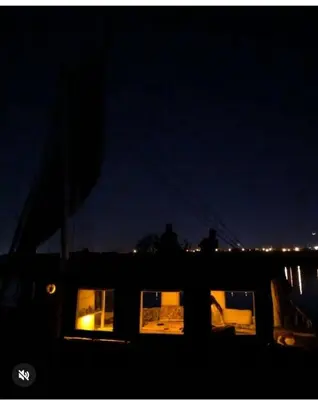 a group of people standing on a boat at night at faloka Farha Camp in Aswan