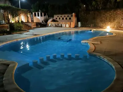 a swimming pool with blue water at night at Lux Gardenhouse pool WiFi Private garden Hurghada in Hurghada