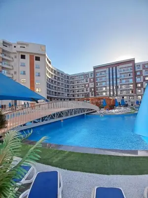 a bridge over a swimming pool with chairs and buildings at C'est la vie Golden in Hurghada