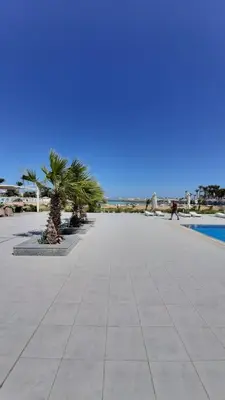 a walkway with palm trees and a swimming pool at Hurghada Ägypten Scandic Resort in Hurghada